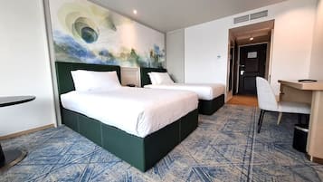 A hotel room with two beds, a desk, and a chair.