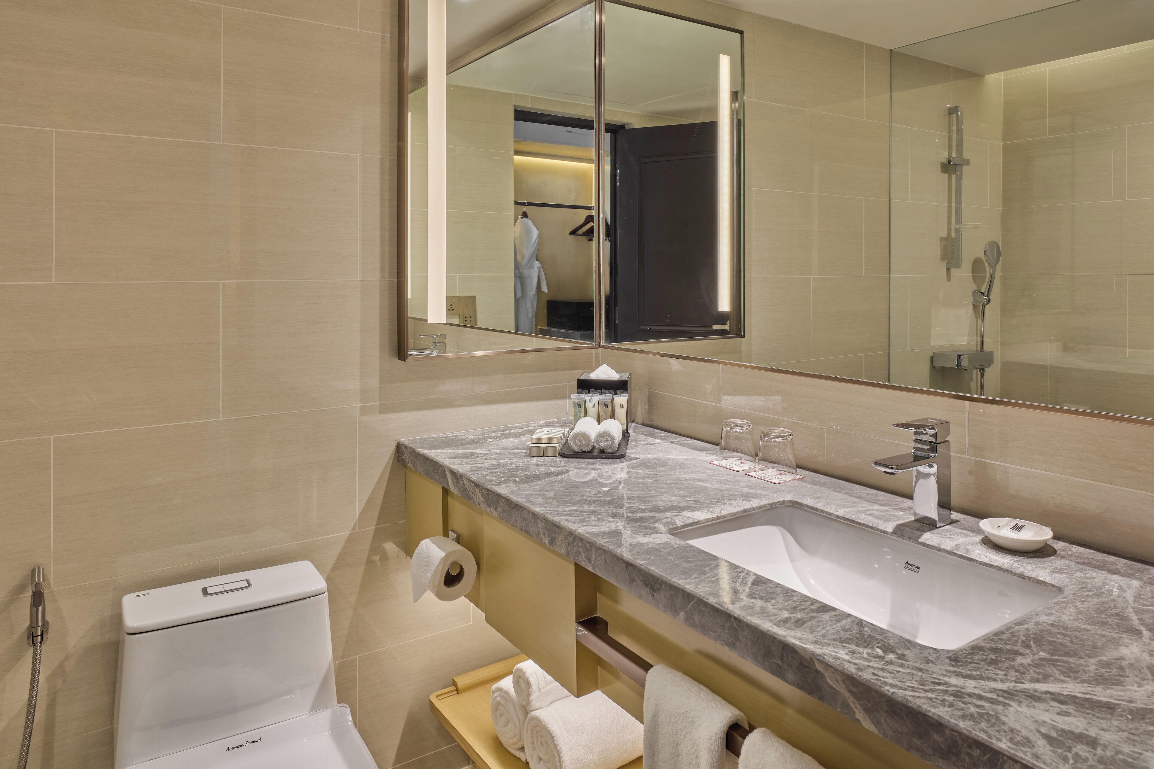 A modern bathroom with a large mirror, two sinks, a shower, and a toilet.