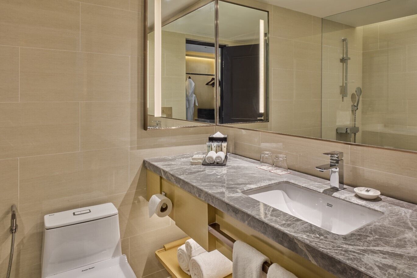 A modern bathroom with a marble countertop, two sinks, a toilet, and a shower.