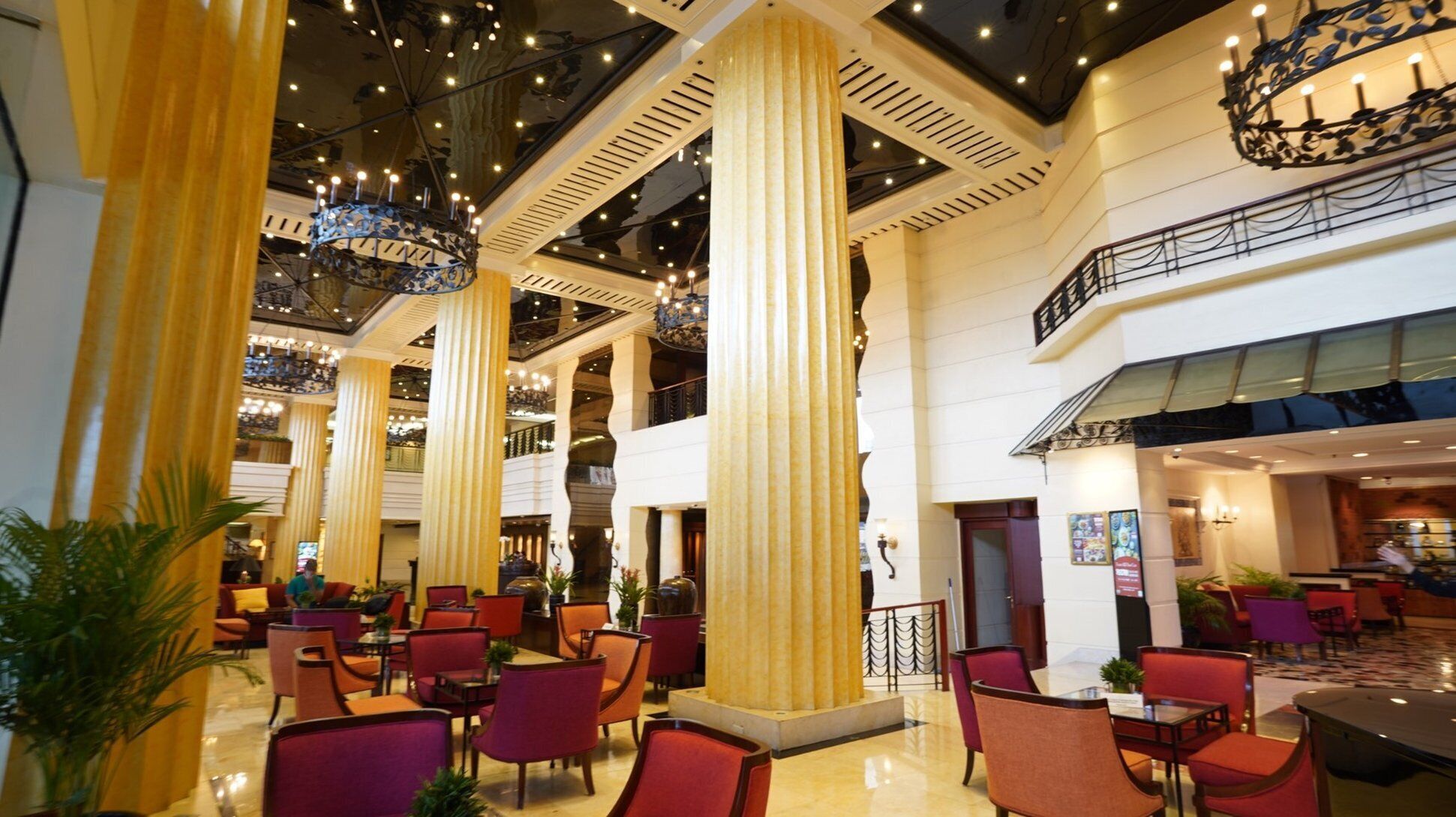 A spacious lobby with high ceilings, large columns, and a grand chandelier.
