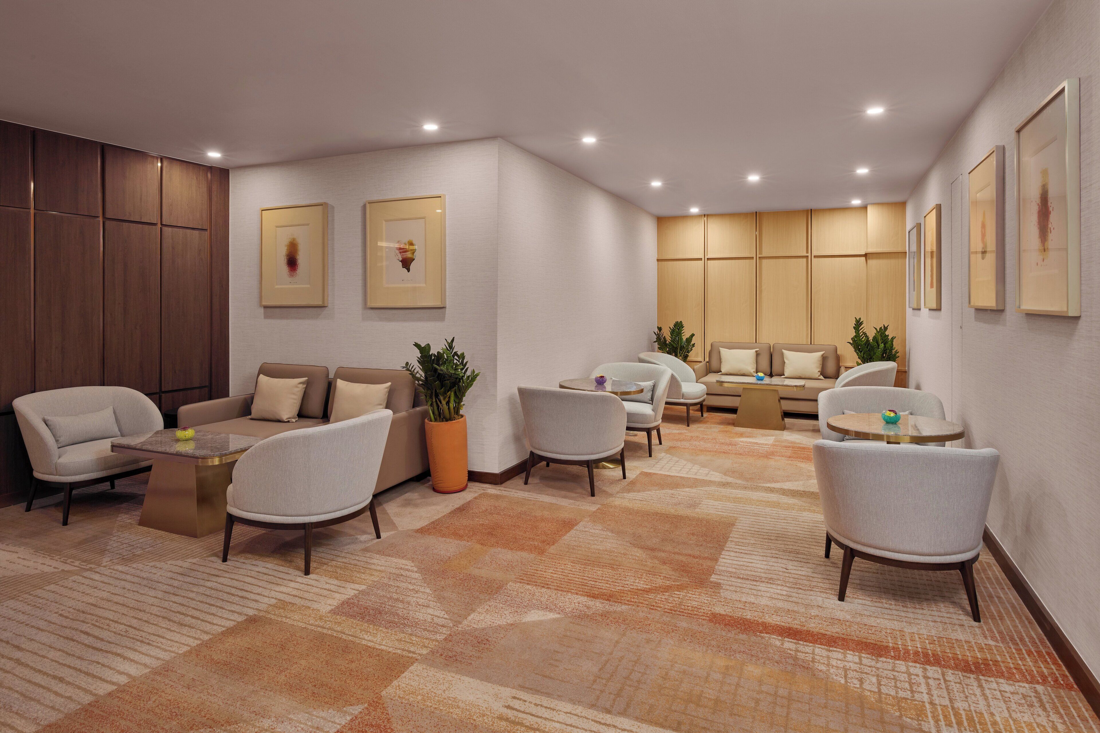 A modern hotel lobby with a seating area, a reception desk, and framed artwork on the walls.