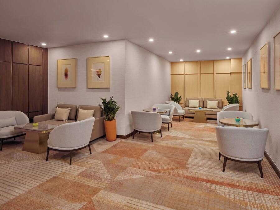 A modern hotel lobby with a seating area, a reception desk, and framed artwork on the walls.
