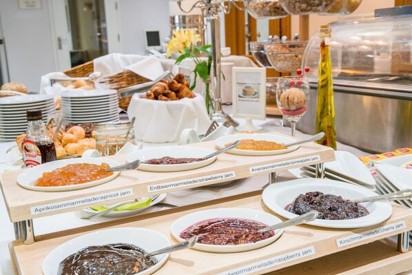 Een ontbijtbuffet met verschillende jamsoorten en gebak.