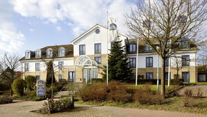 A hotel with a large glass entrance, multiple windows, and a flagpole with a flag. - Best Western Hotel Helmstedt am Lappwald (Helmstedt)