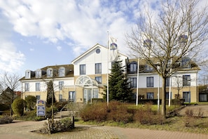 A hotel with a large glass entrance, multiple windows, and a flagpole with a flag. - Best Western Hotel Helmstedt am Lappwald (Helmstedt)