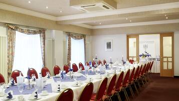 A conference room with a long table set for a meeting, equipped with chairs, tables, and various tableware.