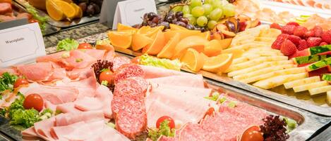 A buffet with various food options including meats, cheeses, fruits, and vegetables.
