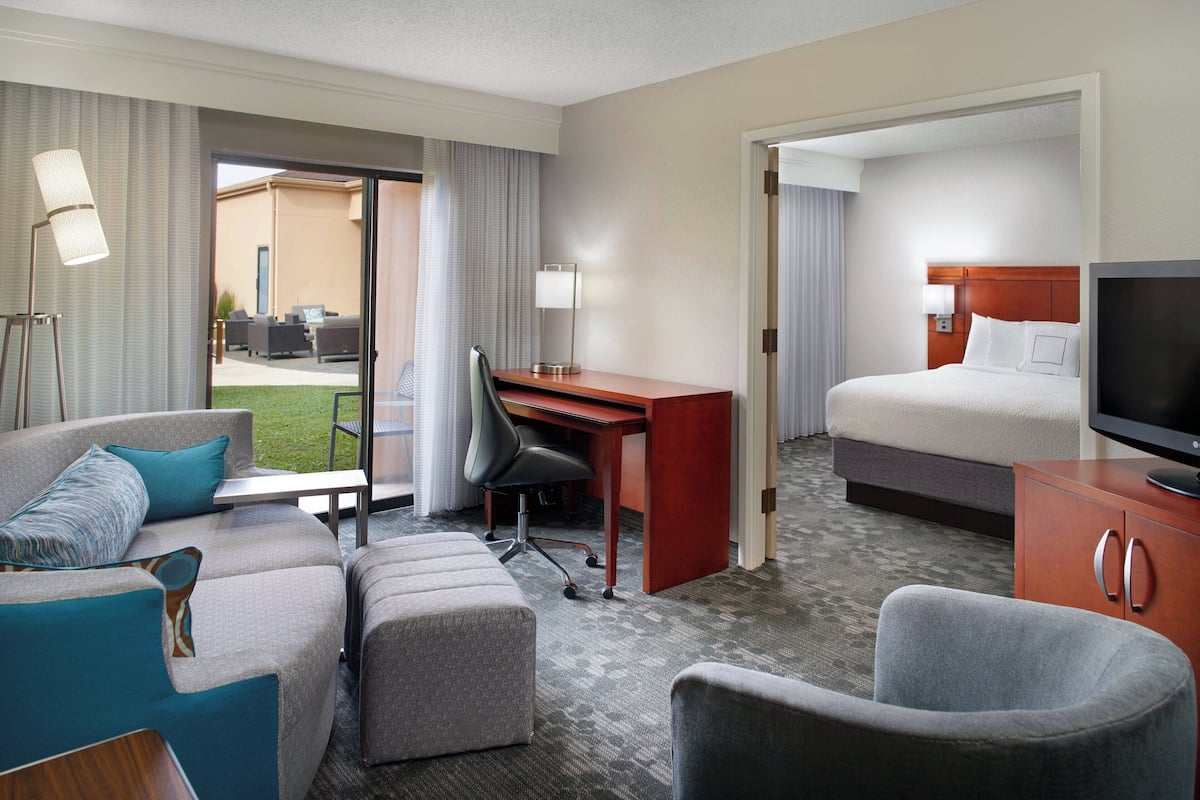 Een hotelkamer met een bed, bureau, bank, televisie en uitzicht op het buitengebied.