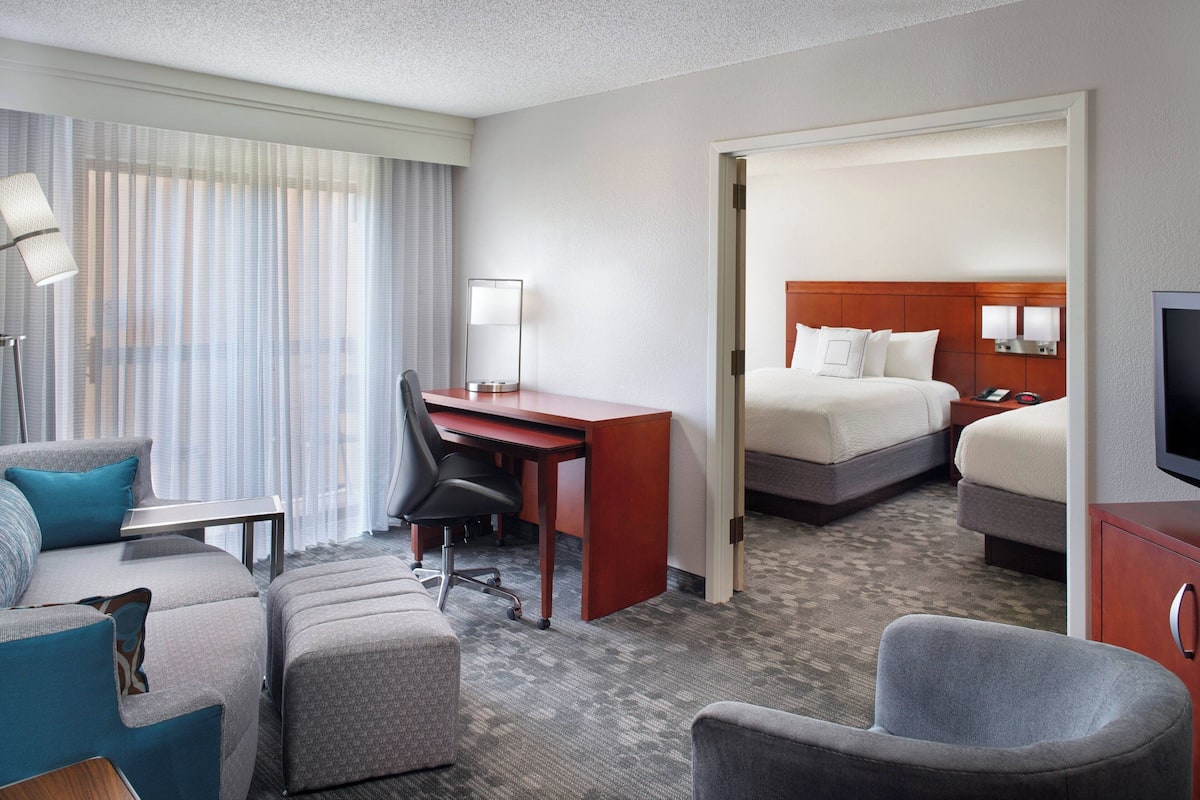 Een hotelkamer met een bed, een bureau, een stoel, een televisie en een bank.