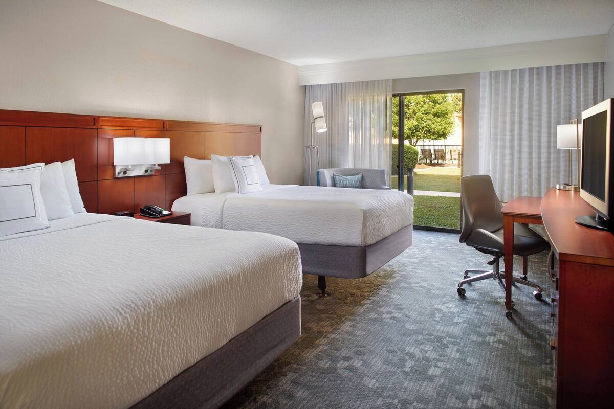 Een hotelkamer met twee bedden, een bureau, een stoel en een televisie.