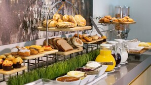 Buffet com diversos pães, patisseria e acompanhamentos.