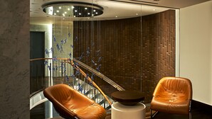 Um hall moderno com parede de madeira, guarda-corpo de vidro e duas poltronas de couro.