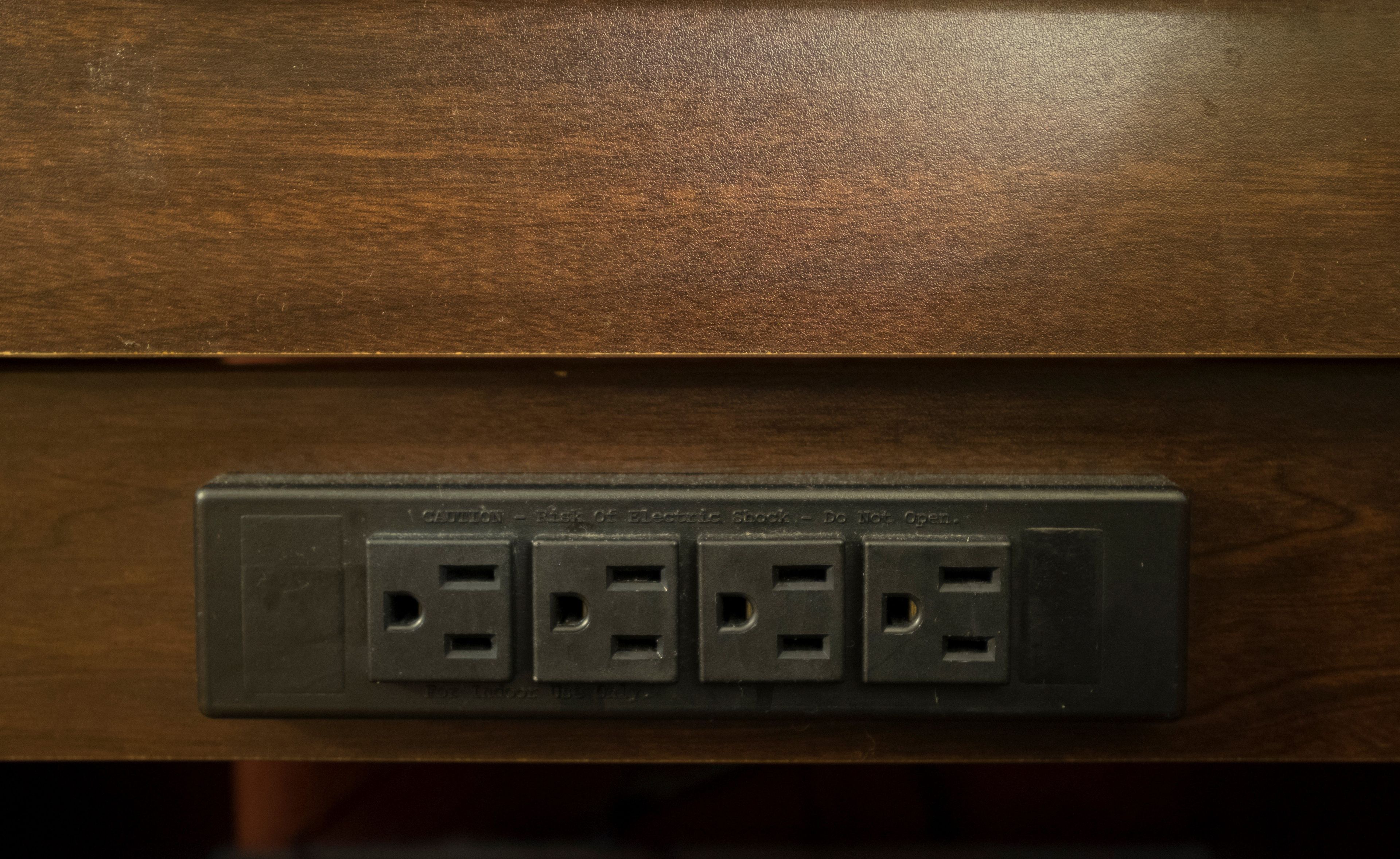 A wooden surface with a black electrical outlet with four sockets.