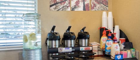 A kitchen counter with a coffee maker, a water dispenser, and various coffee pods.