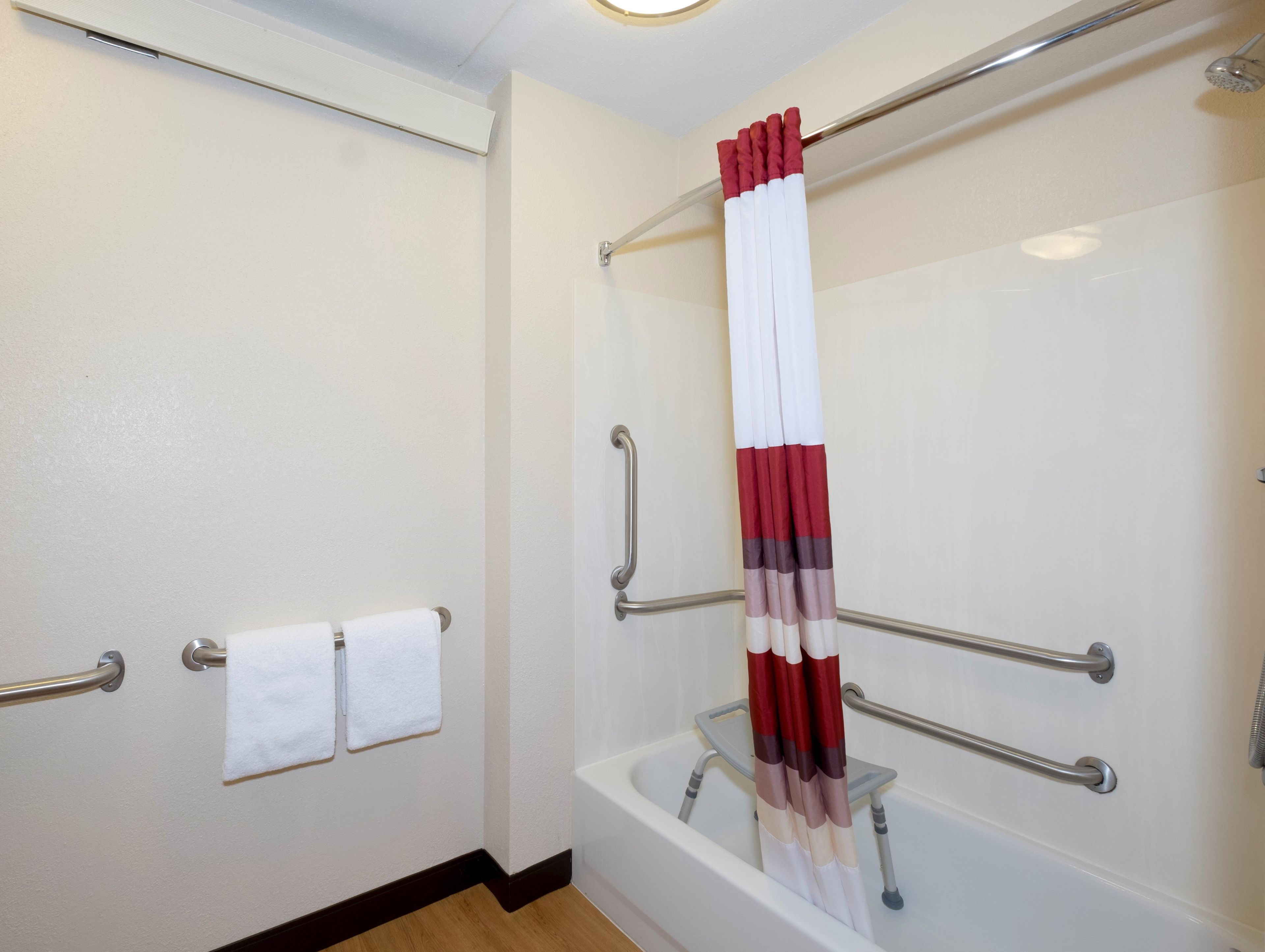 Ein Badezimmer mit Badewanne, einer Duschkabine mit Glastür und einer Handstange.