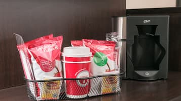 A coffee machine and a basket with coffee pods and a disposable cup.