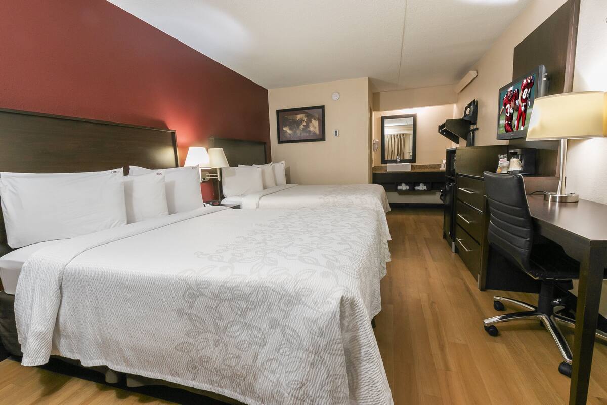 Una habitación de hotel con una cama grande, un escritorio, una silla, un televisor y un baño.