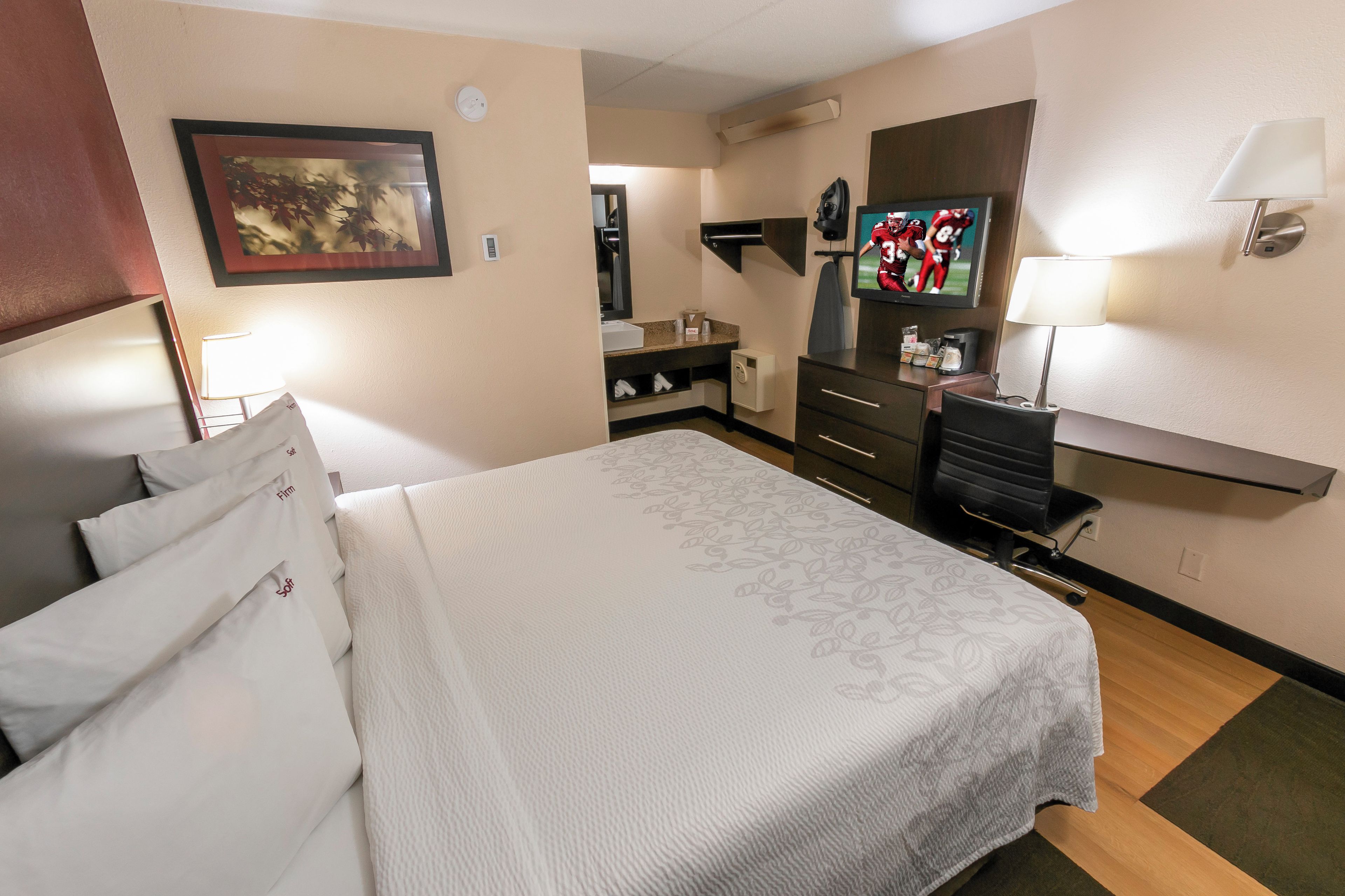 Ein Hotelzimmer mit Bett, Schreibtisch, Fernseher und Spiegel.