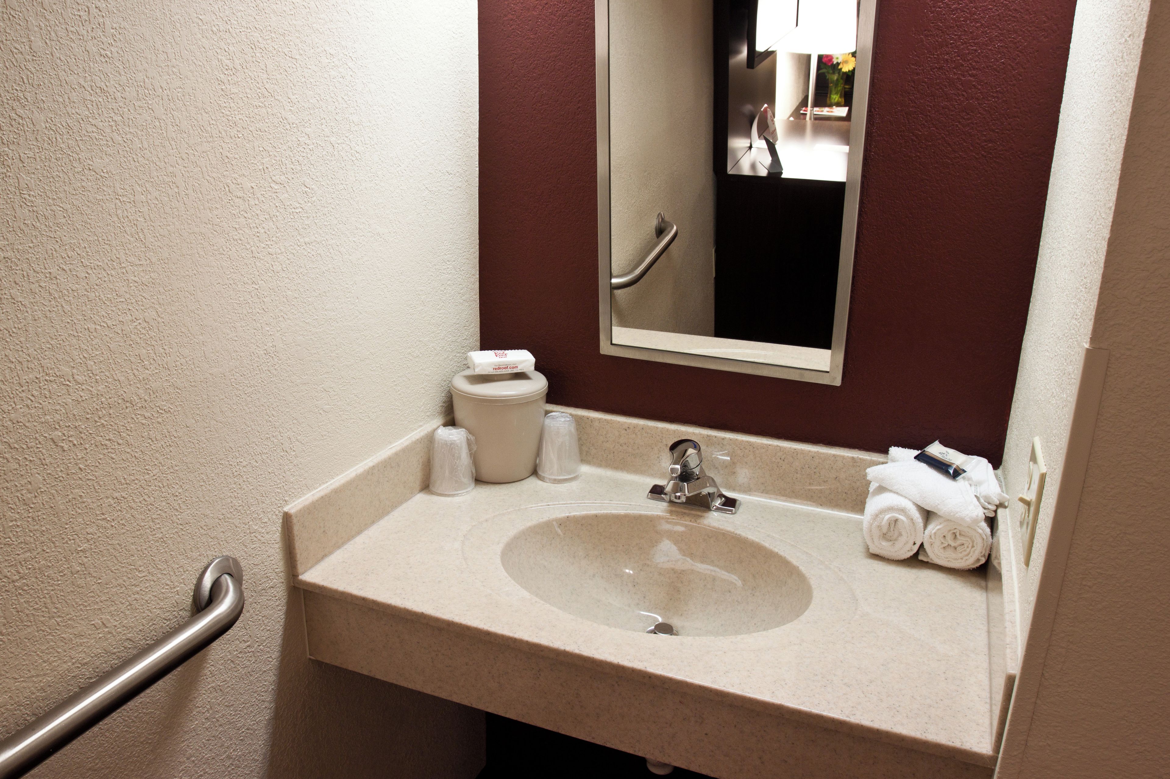 A bathroom with a sink, mirror, and towel rack.