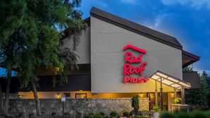 Un hôtel Red Roof Plus avec une façade en pierre, une entrée couverte et un parking.