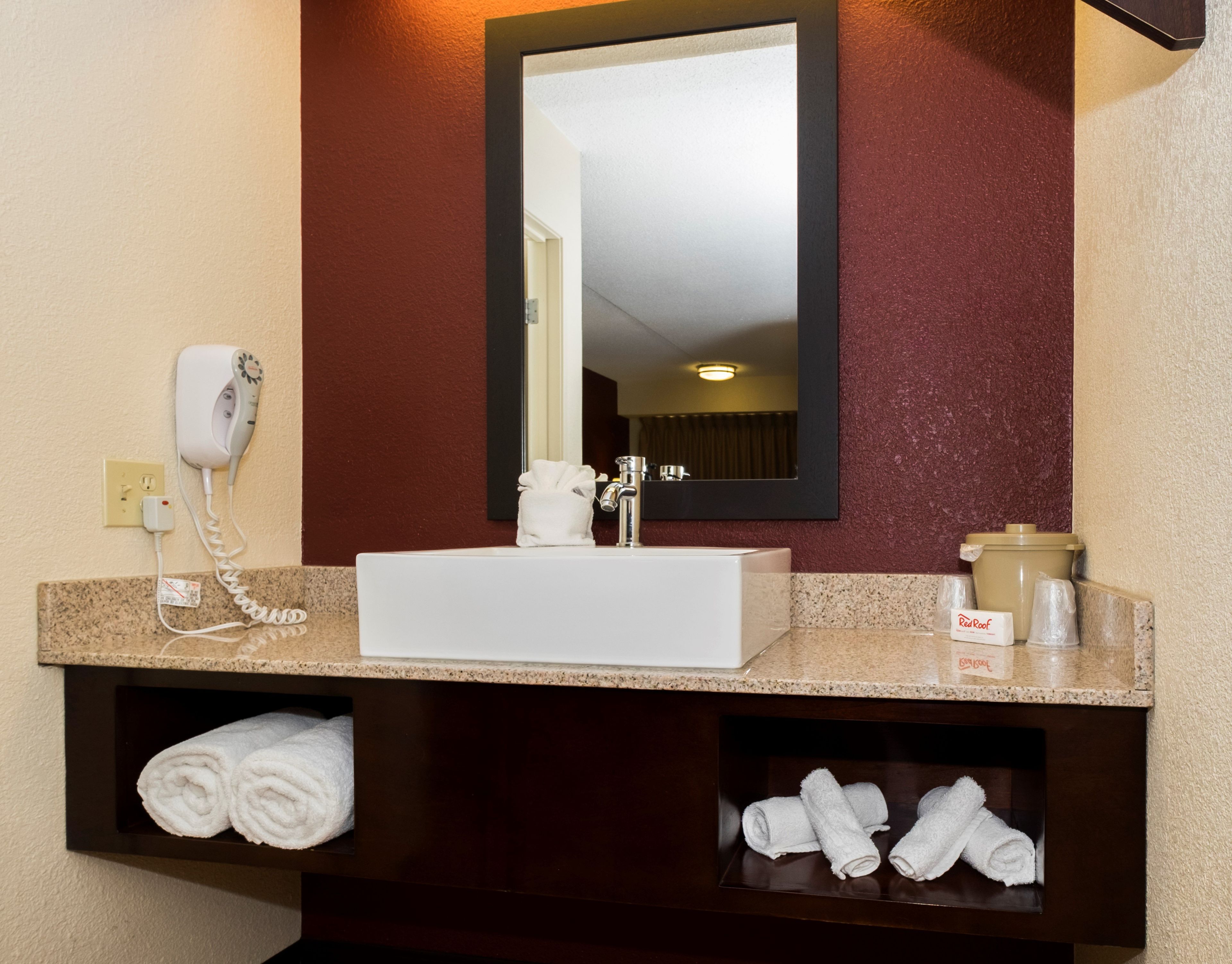 Une salle de bain avec un lavabo blanc, un miroir, un sèche-cheveux et des serviettes.
