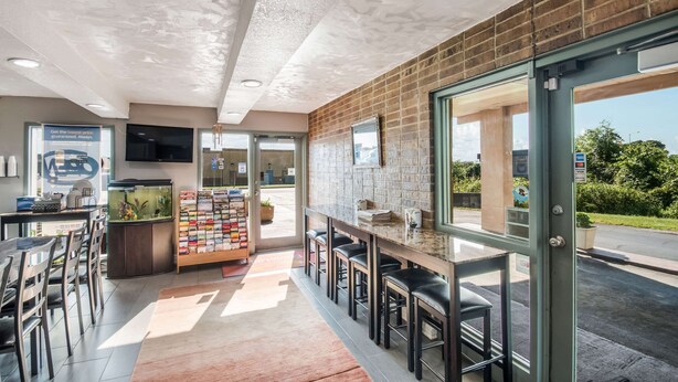 A modern cafe with a brick wall, a bar area, and a seating section. - Econo Lodge Kearney - Liberty (Kearney)