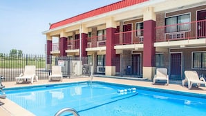A hotel with a swimming pool, multiple balconies, and lounge chairs. - Econo Lodge Kearney - Liberty (Kearney)