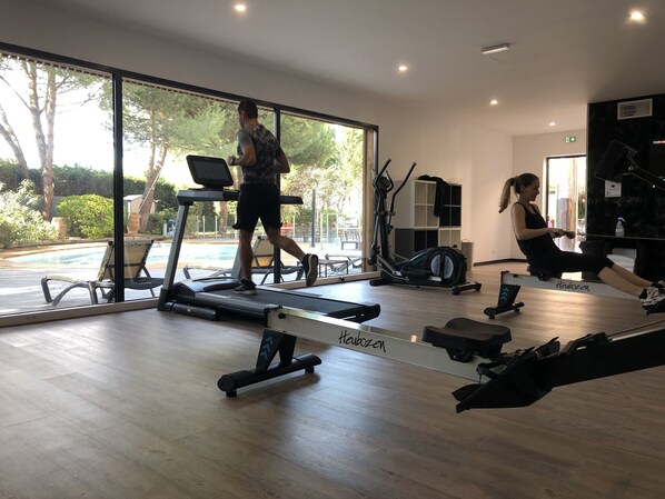 A gym with a treadmill, rowing machine, and exercise equipment.