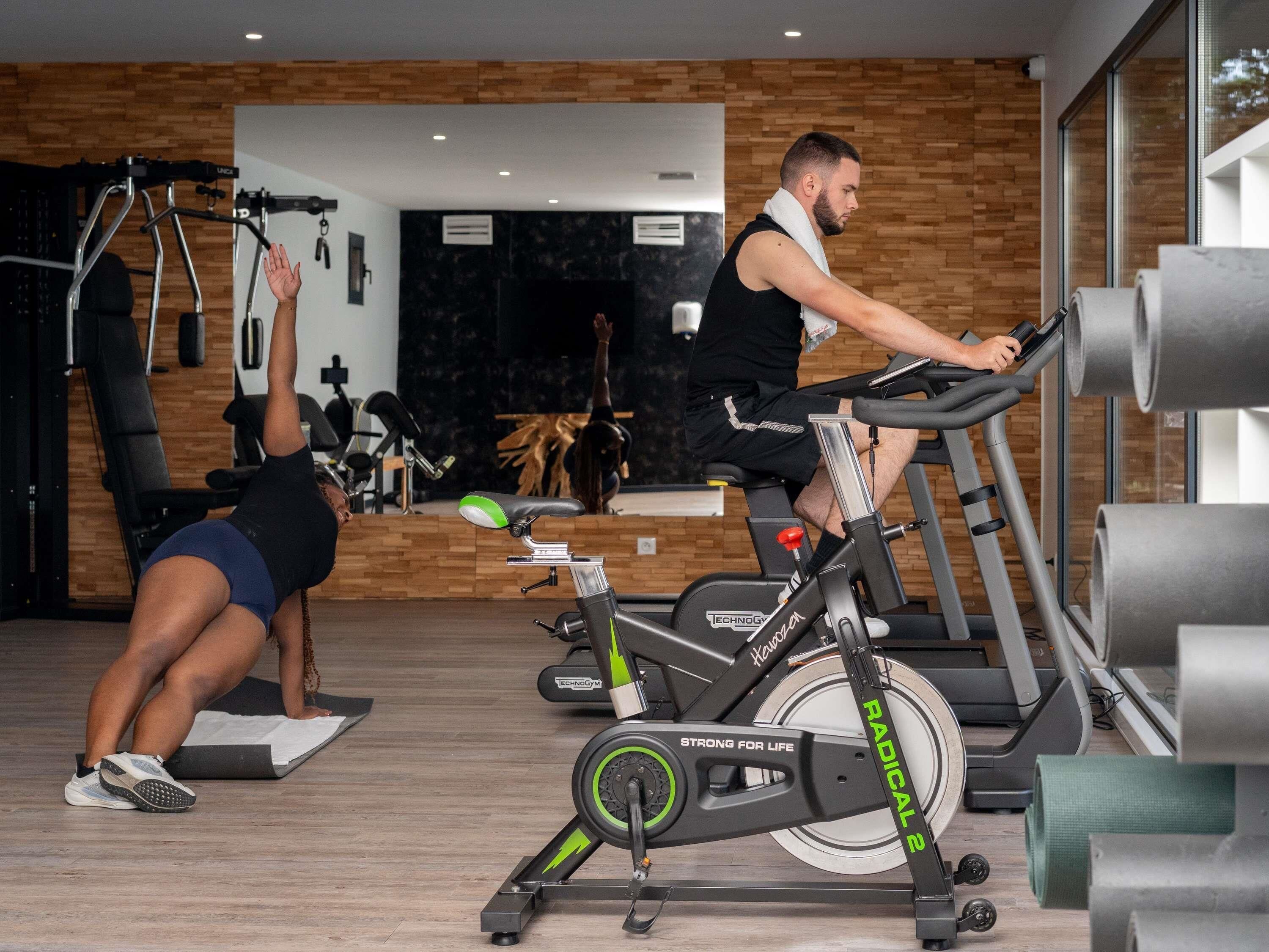 Een sportschool met trainingsapparatuur, een spiegel en een houten wand.
