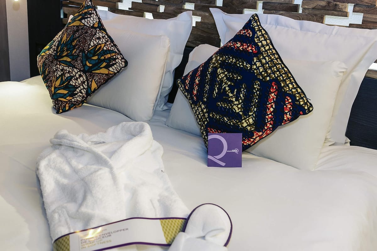Un sofá blanco con almohadas estampadas, una bata blanca y una etiqueta morada.