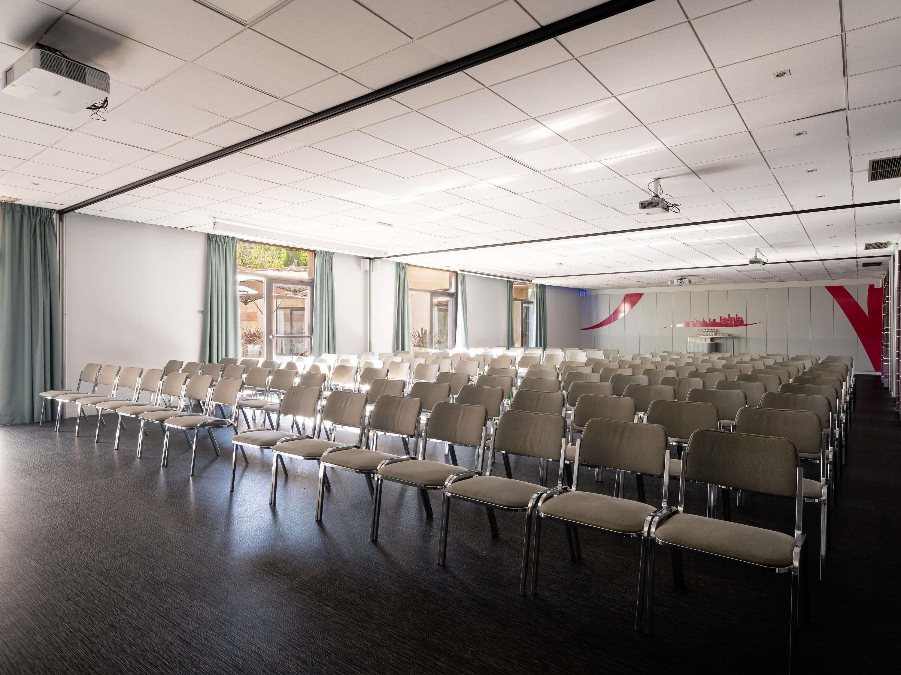 A conference room with rows of chairs, a projector, and a large window.