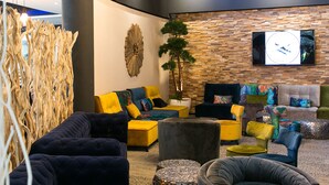 A modern lounge area with a variety of seating options, a decorative wall, and a mounted television.