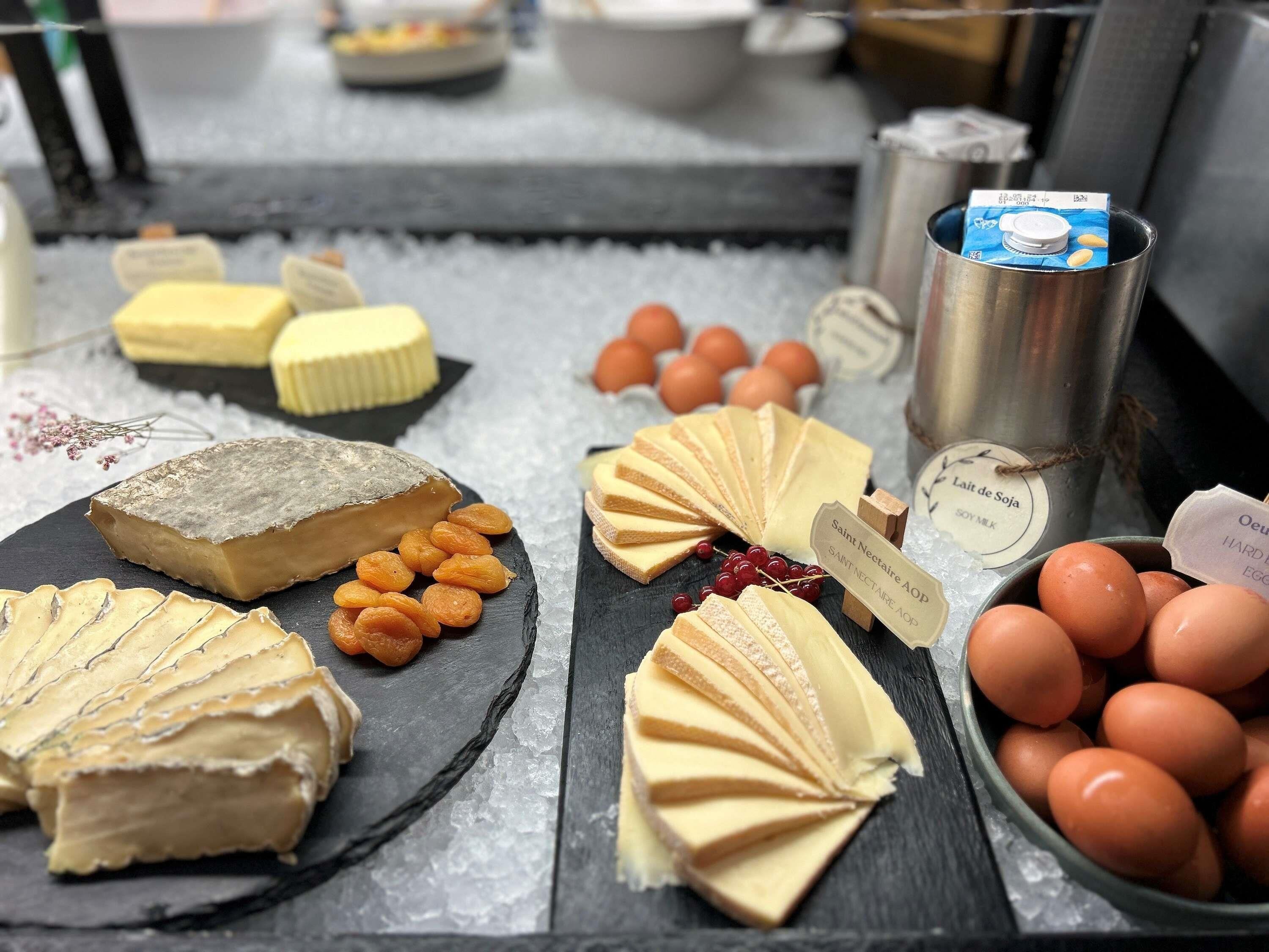 Une variété de fromages, de fruits secs et d’œufs présentés sur une ardoise avec de la glace.
