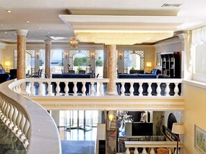 Experience the grandeur of our lobby, featuring a spacious open design, a balcony with a view, and a grand staircase.