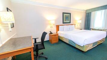 Ein Hotelzimmer mit Bett, Schreibtisch, Stuhl, Nachttisch und zwei Wandleuchten.