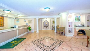 A hotel lobby with a reception desk, a dining area, and a fireplace.