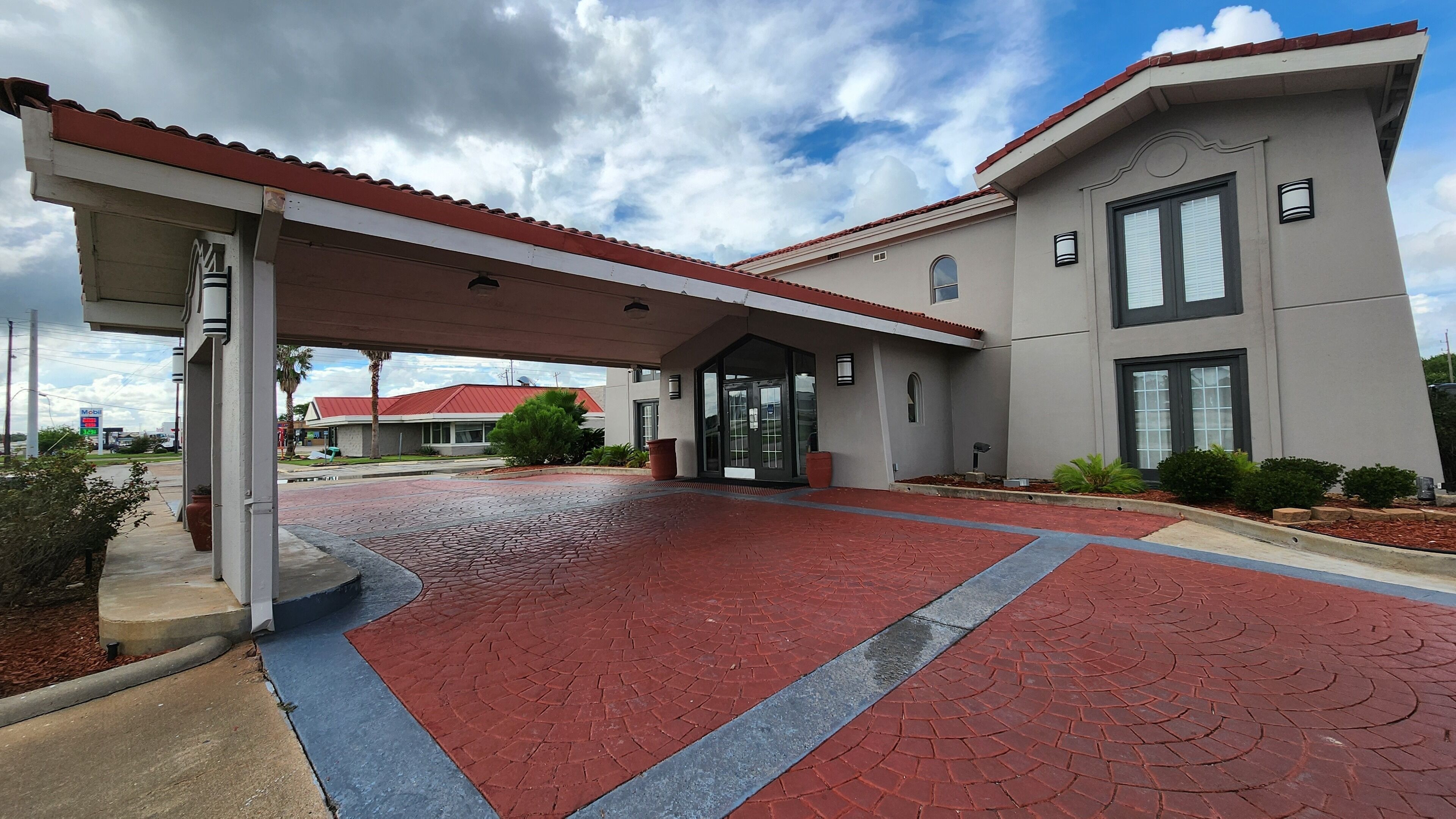 Un edificio moderno con ingresso coperto e un vialetto in mattoni rossi che vi conduce.