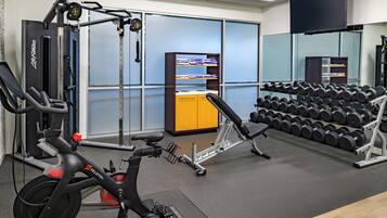 A gym with exercise equipment, a weight rack, and a mirrored wall.