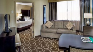 A hotel room with a bed, a sofa, a desk, and a TV. - Embassy Suites by Hilton St. Louis Airport (Bridgeton)
