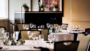 A restaurant with tables set for dining, chairs, and a decorative plant in the background. - Chicago Marriott Suites Deerfield (Deerfield)
