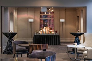 A hotel lobby with a reception desk, seating area, and artwork on the walls.