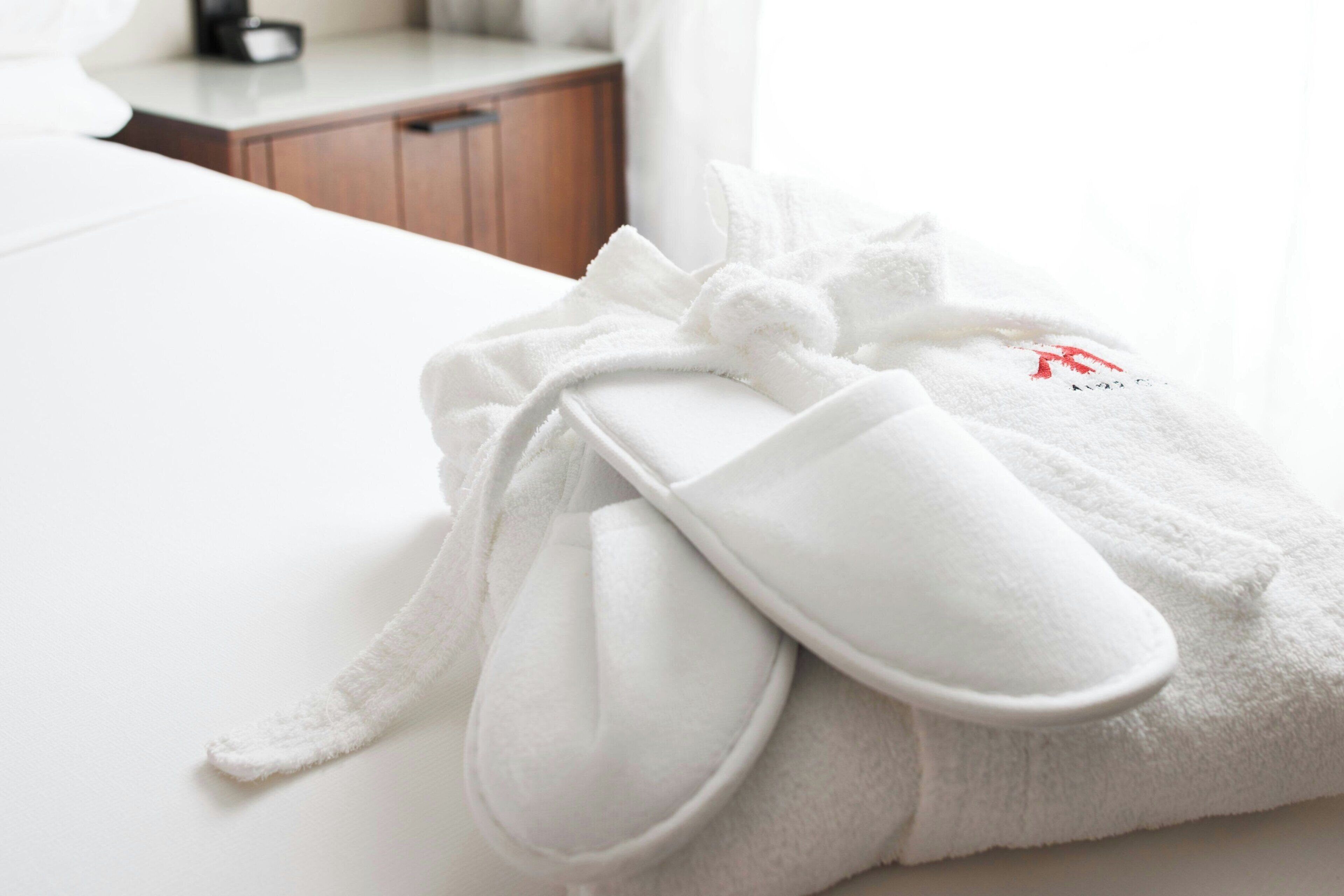 A white bathrobe with a bow on a bed.