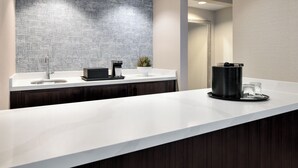 A modern bathroom with a white countertop, a sink, a mirror, and a coffee station. - Chicago Marriott Suites Deerfield (Deerfield)