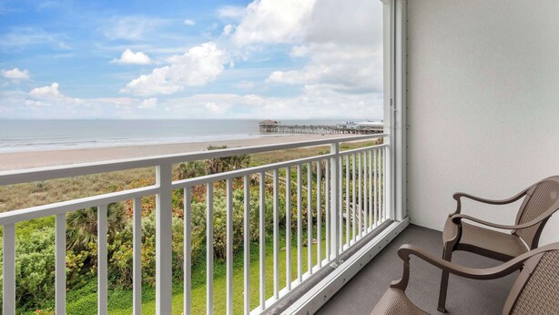 A balcony with a view of the beach and pier, featuring two wicker chairs. - Best Western Cocoa Beach - Port Canaveral (Cocoa Beach)