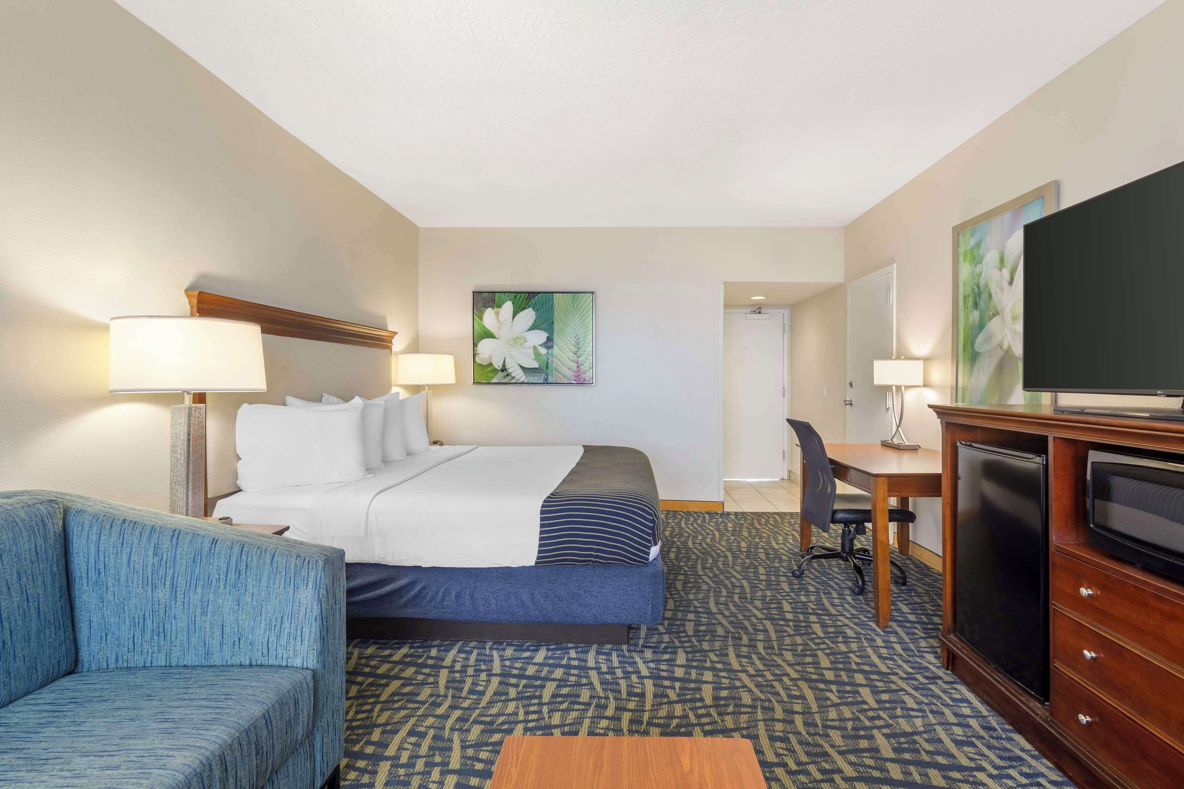 A hotel room with a bed, a desk, a television, and a couch.