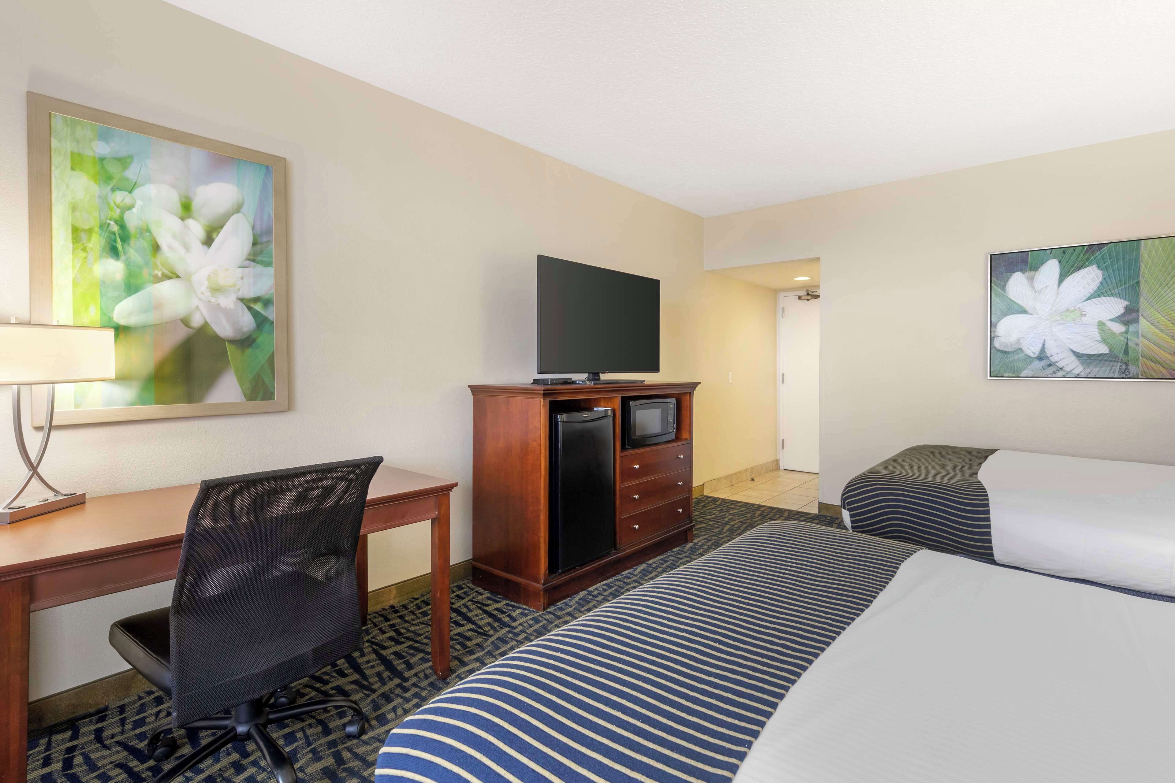 A hotel room with a bed, a desk with a chair, a television, and a dresser.
