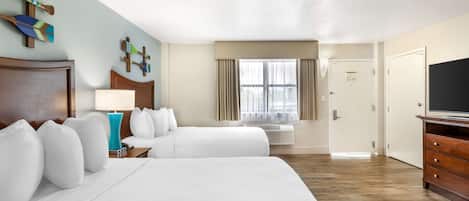 A hotel room with two beds, a TV, a desk, and a window with curtains.