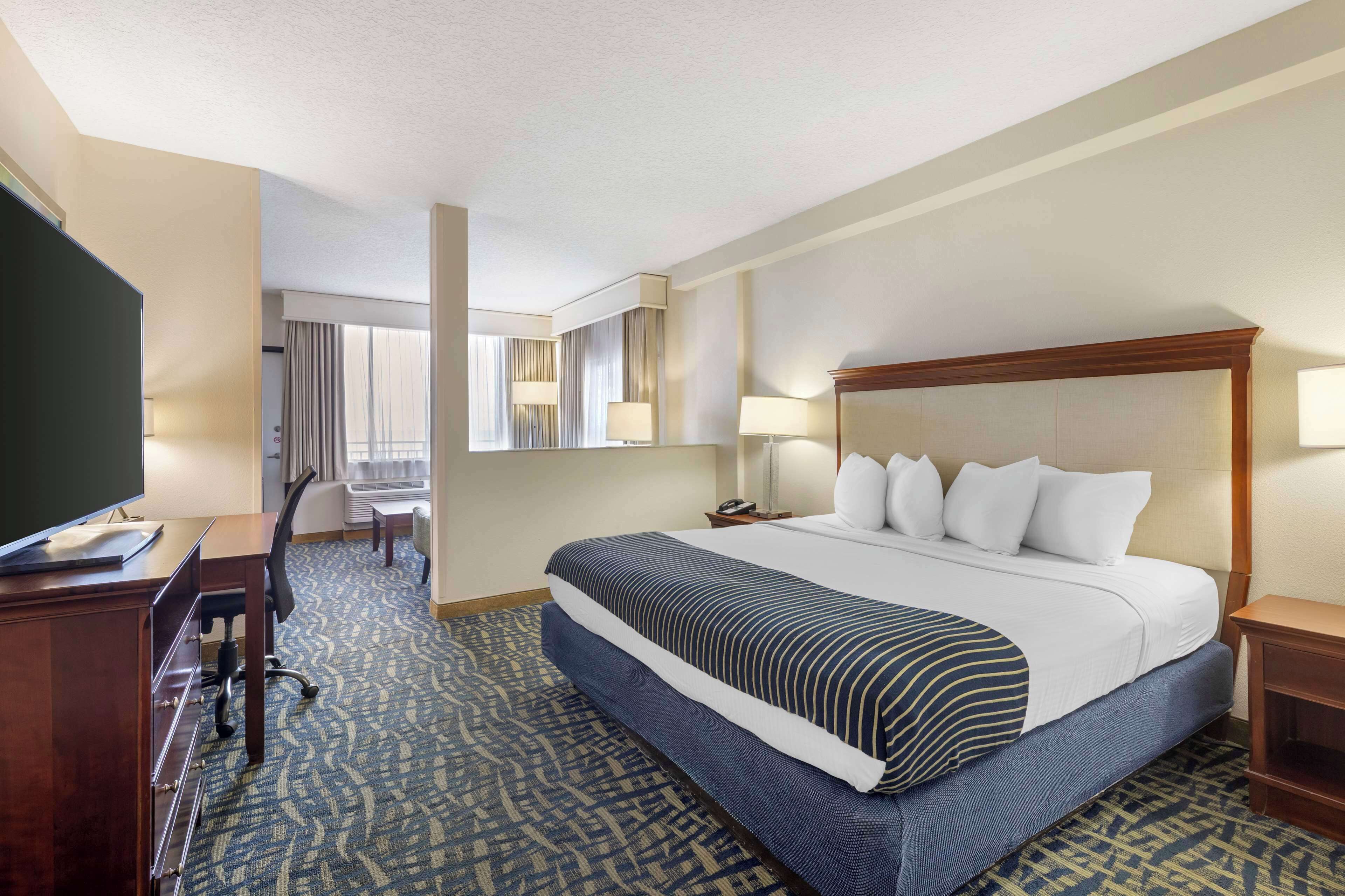 A hotel room with a large bed, a desk, a chair, and a television.