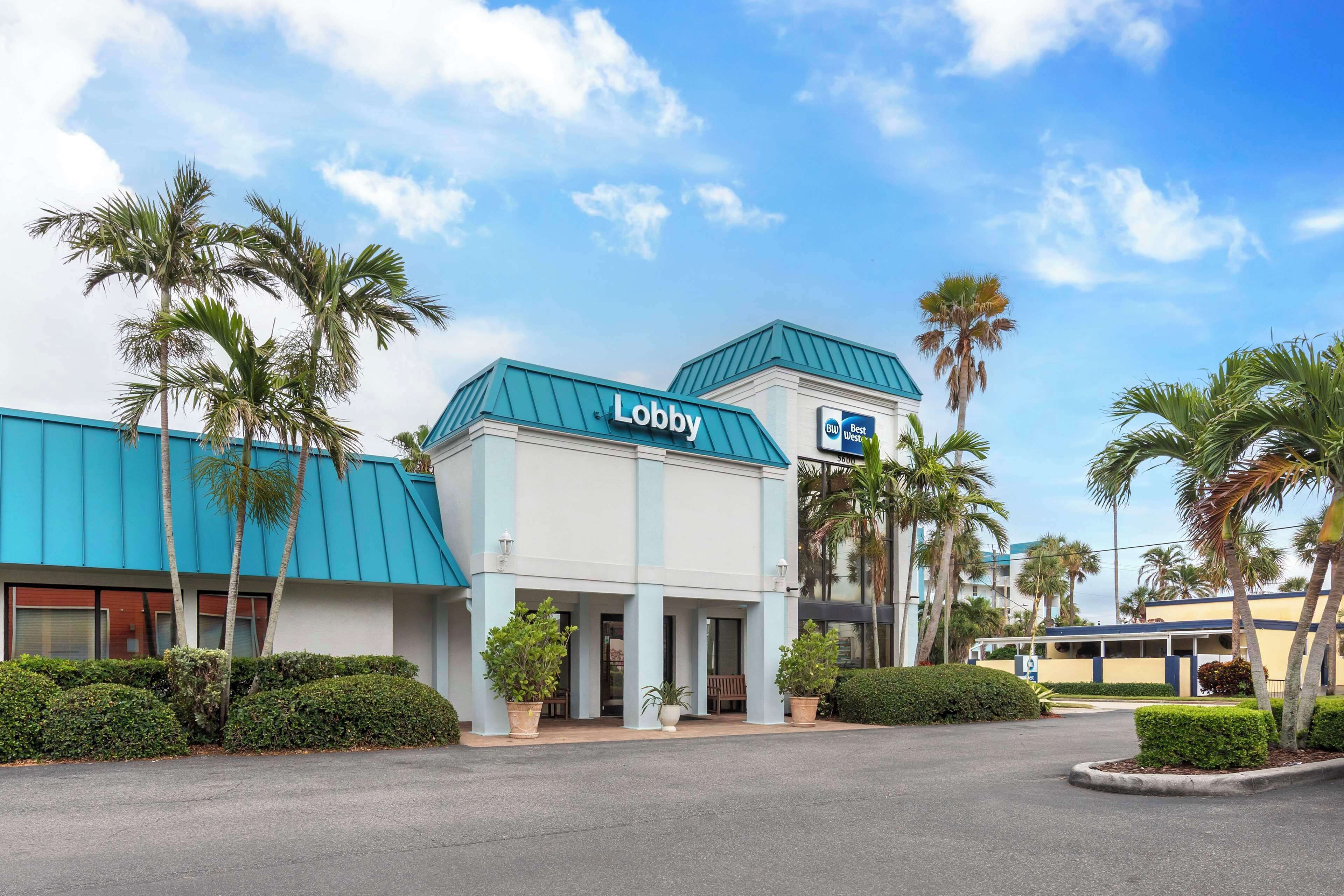 A hotel with a 'Lobby' sign, palm trees, and a blue roof.