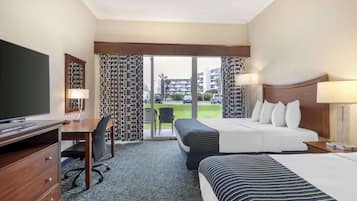 Habitación de hotel con cama, escritorio, televisor y vista a un estacionamiento y edificios.